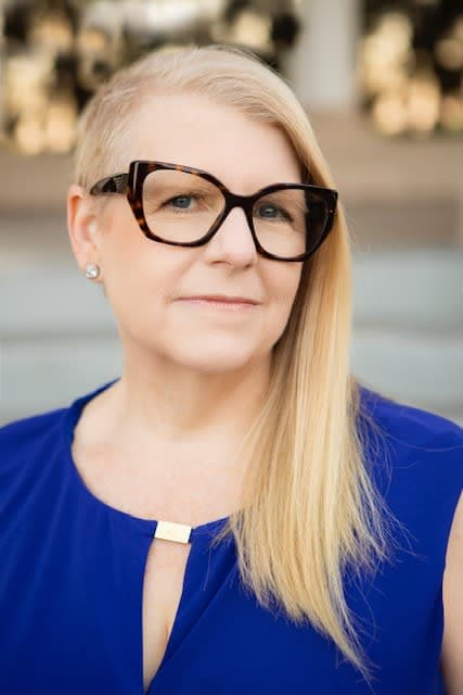 A woman wearing glasses and a blue dress