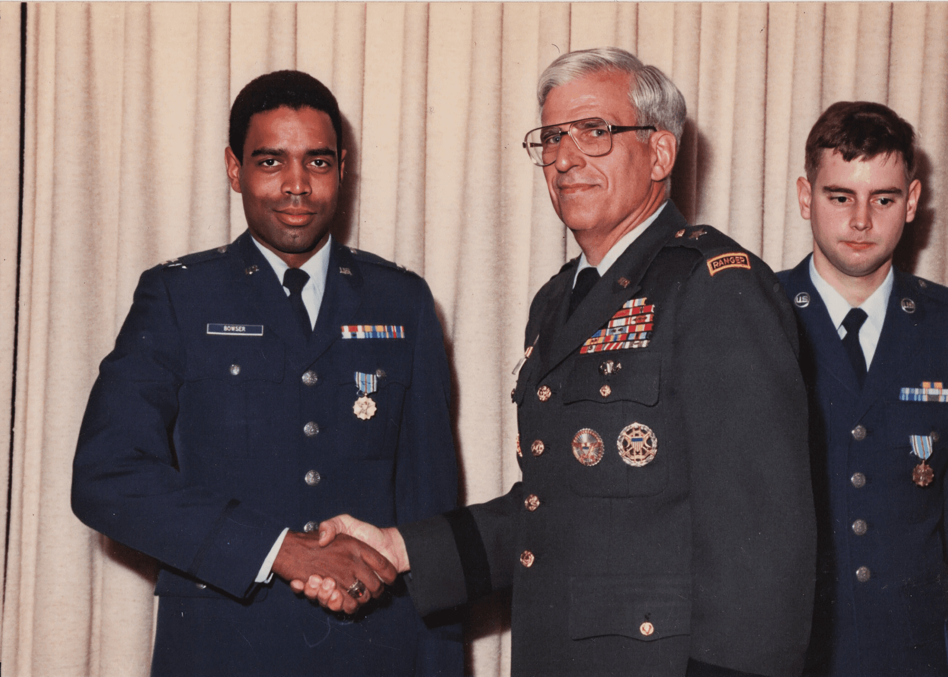A man in a military uniform shaking hands with two other men