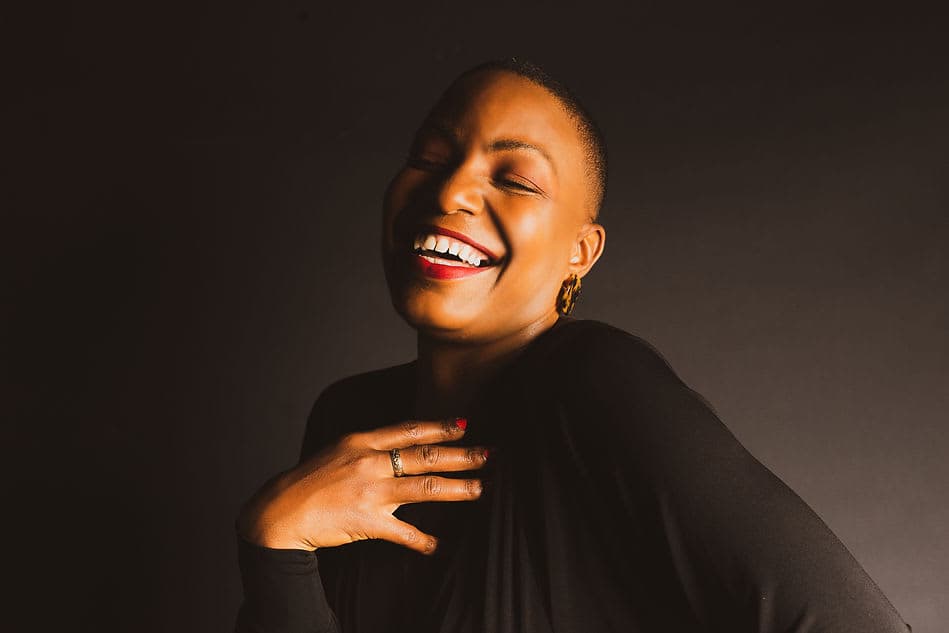 A woman smiling and laughing with her hands on her chest