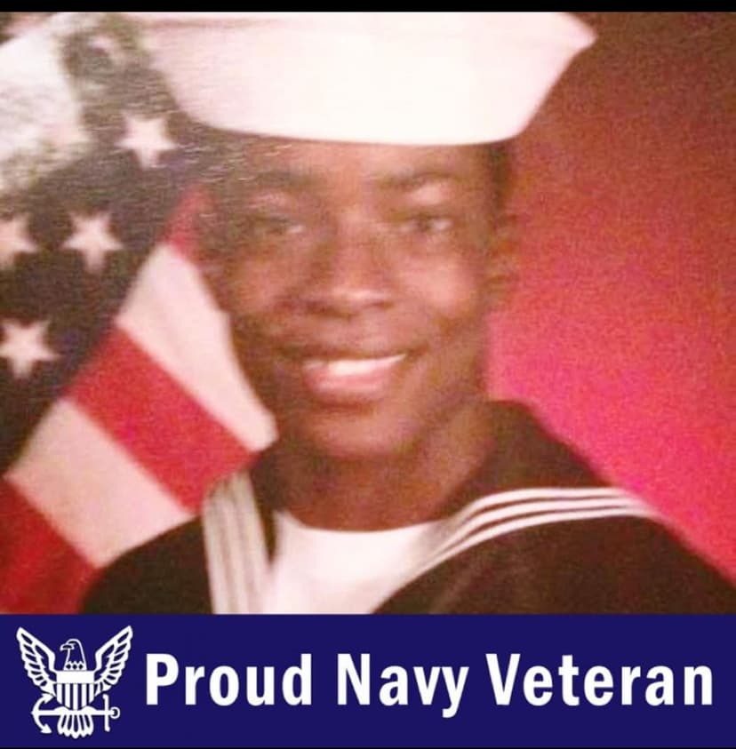 A man in a sailor's uniform in front of an american flag